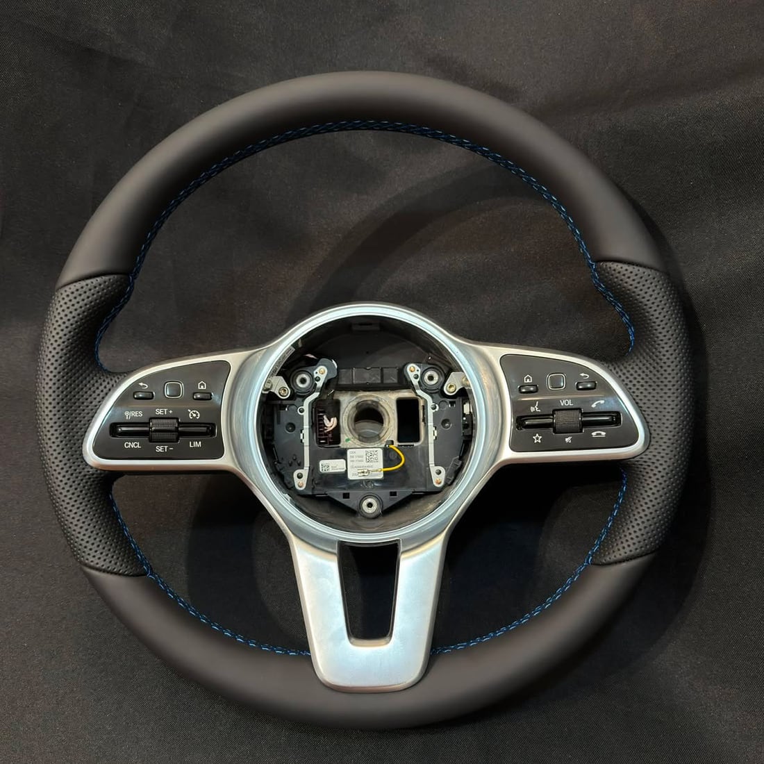 Le même volant Mercedes après réfection — cuir neuf lisse et perforé, coutures bleues
