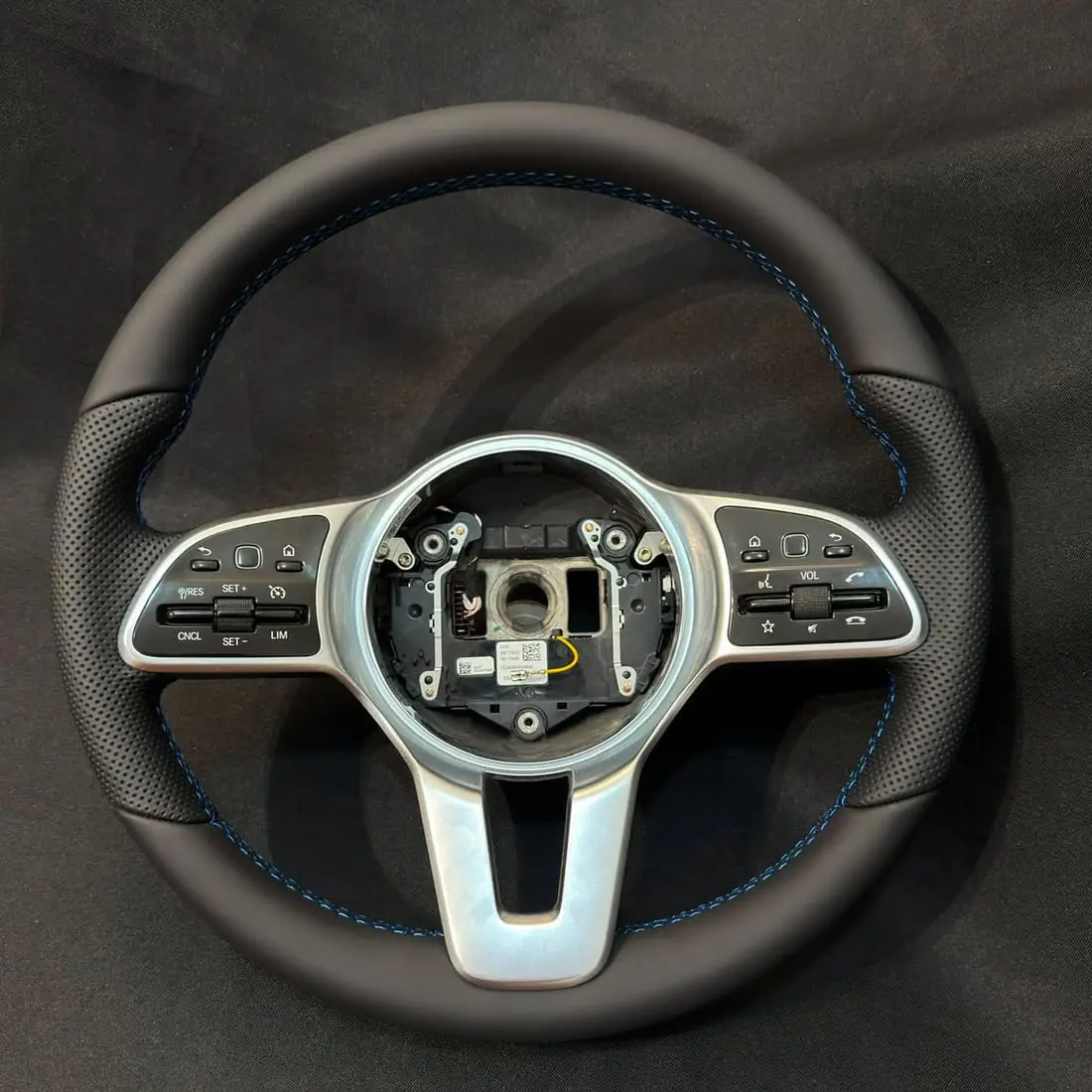 Le même volant Mercedes après réfection — cuir neuf lisse et perforé, coutures bleues